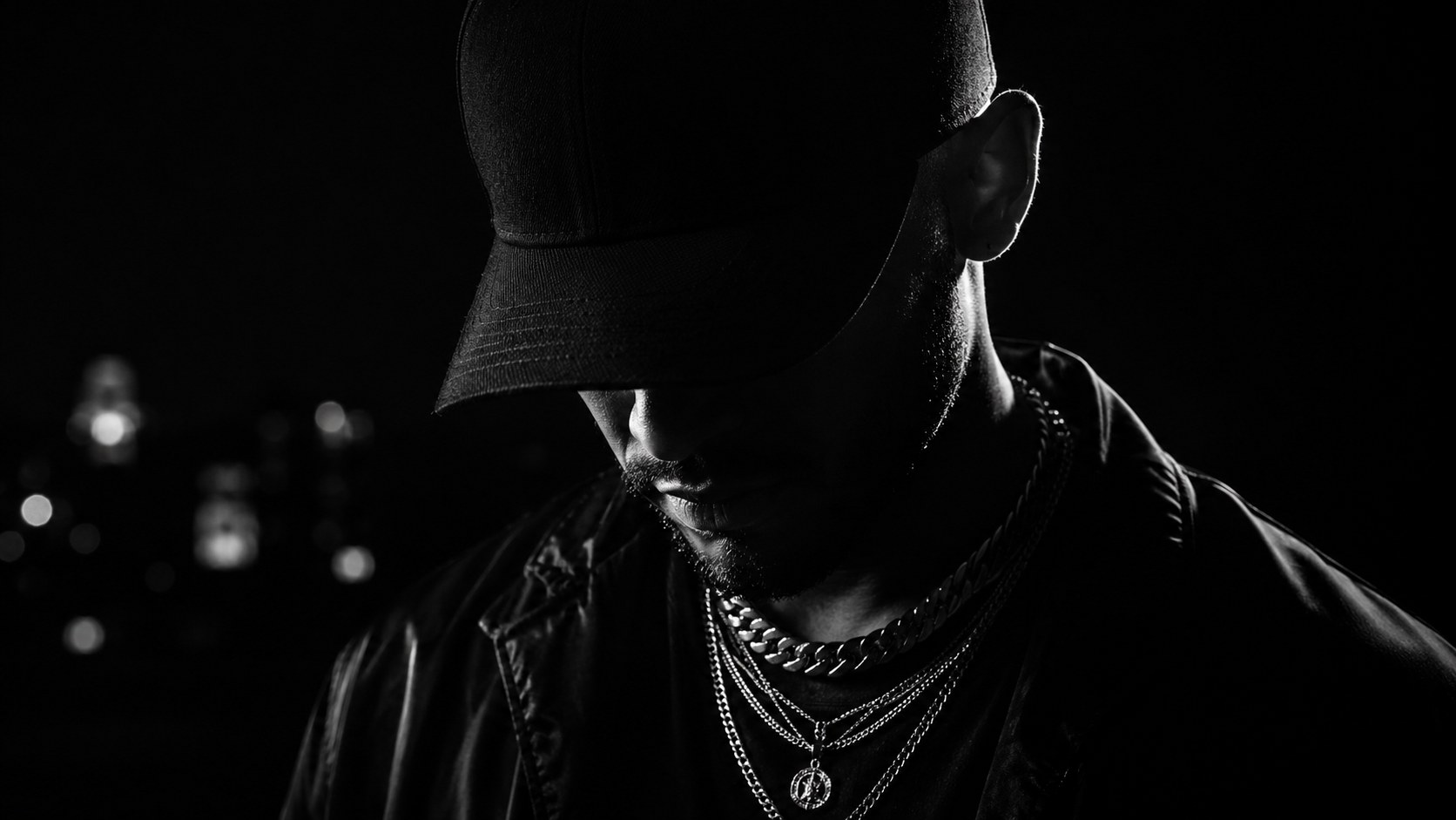 Black and white portrait of an artist wearing a cap and chains