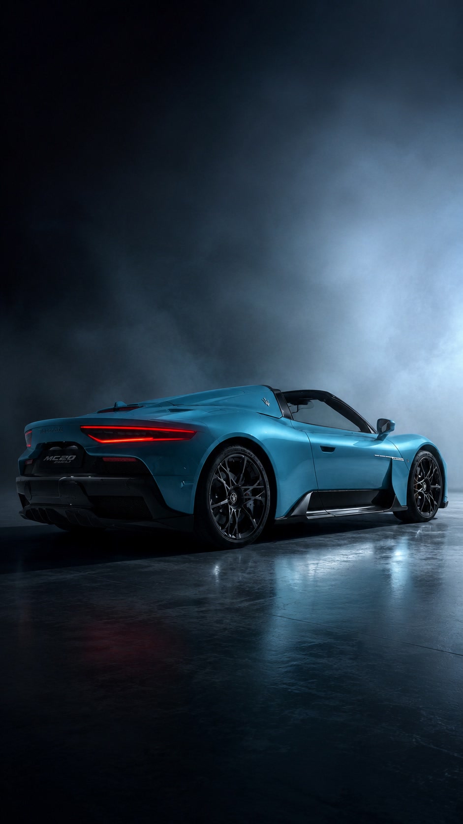 Blue luxury convertible in a dark studio with blue haze and reflections on the floor