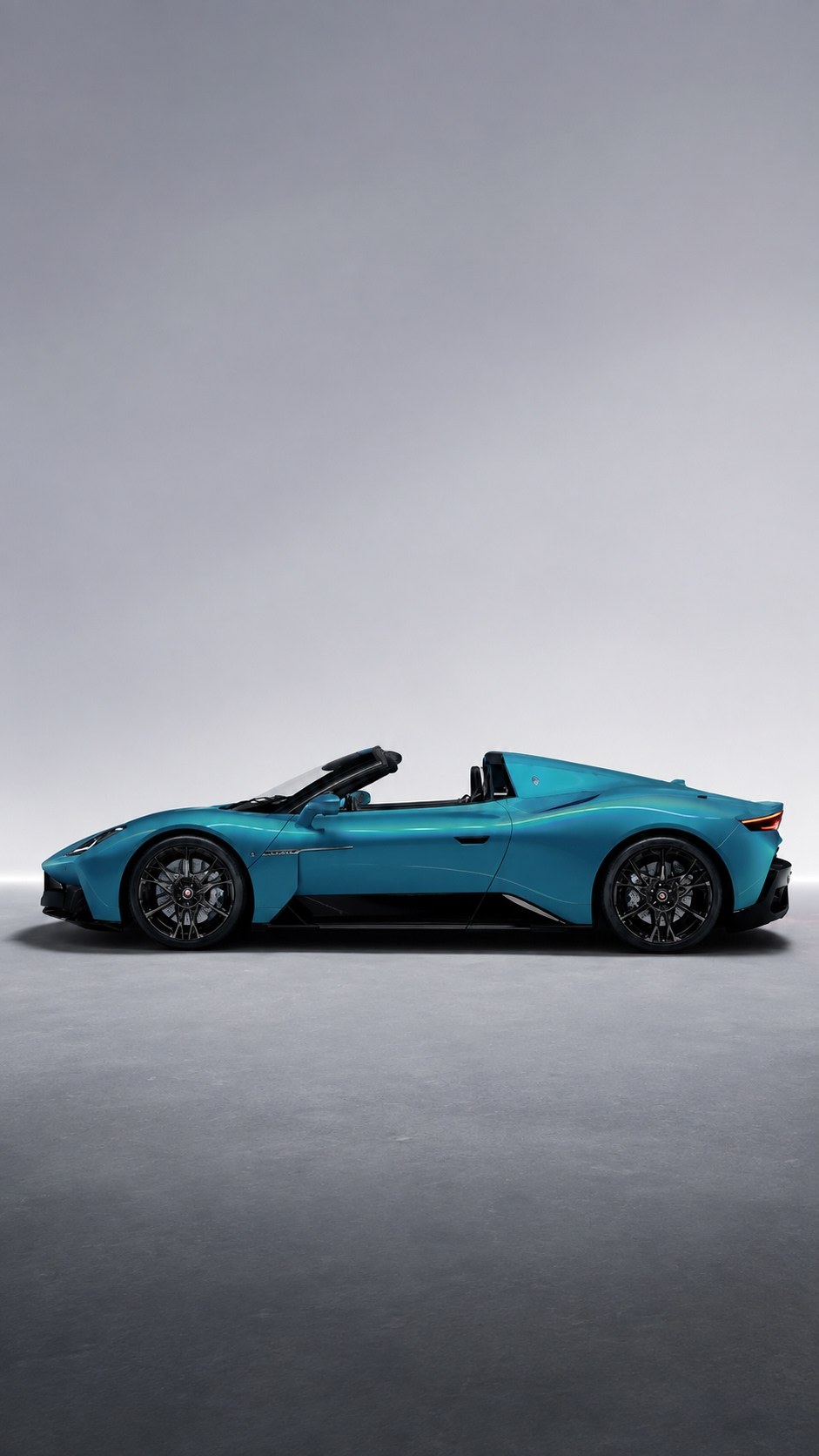 Teal sports car in profile in a grey studio