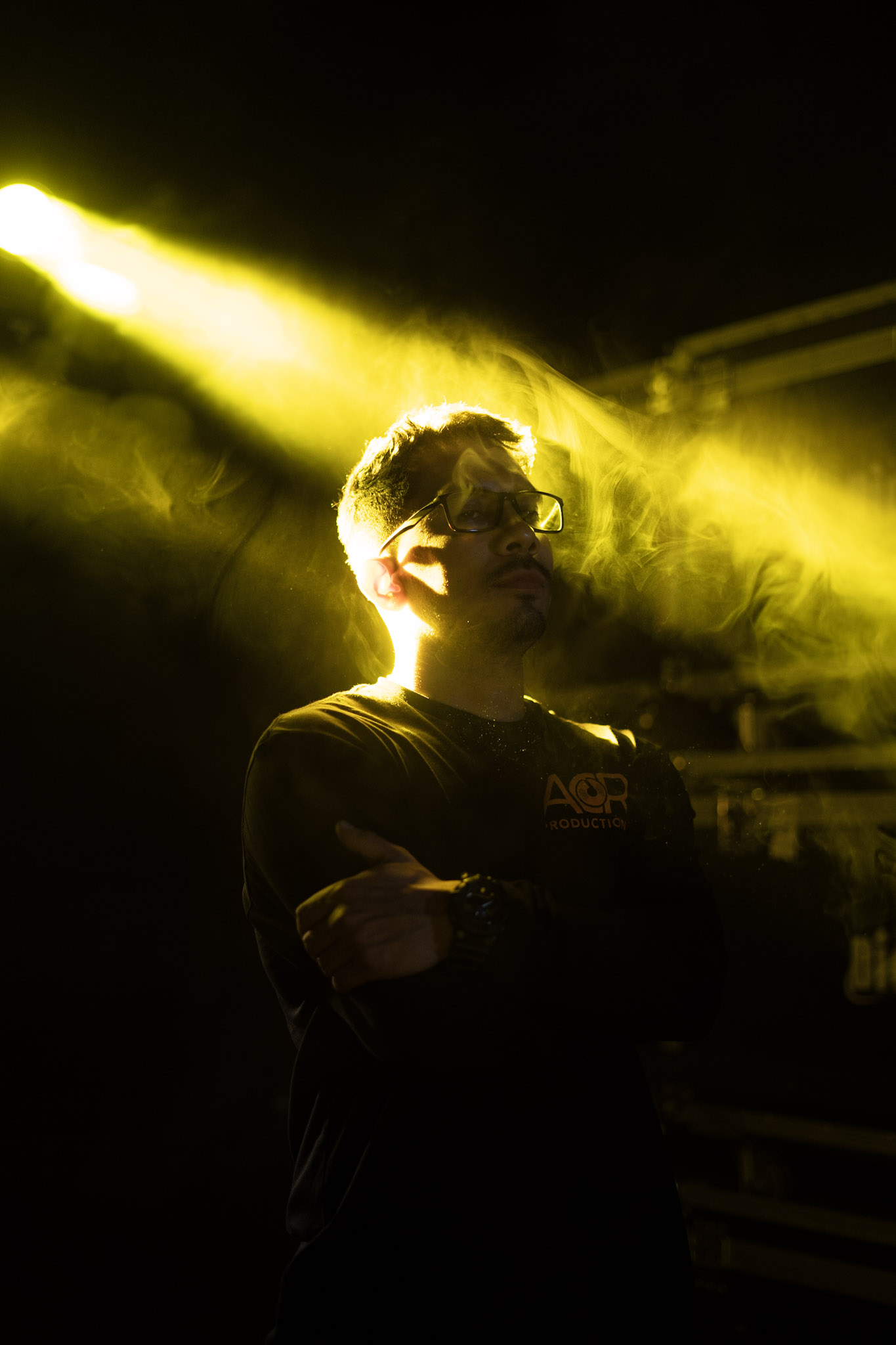 Manuel Quero portrait lit by yellow stage haze, arms crossed